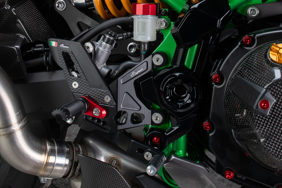 LighTech FTRKA015 fixed-footpeg rearset installed on Kawasaki Z900 SE, right side; optional red footpeg holder and optional black fixed footpeg shown, standard kit uses silver holders and silver fixed footpegs; other motorcycle accessories are not included.