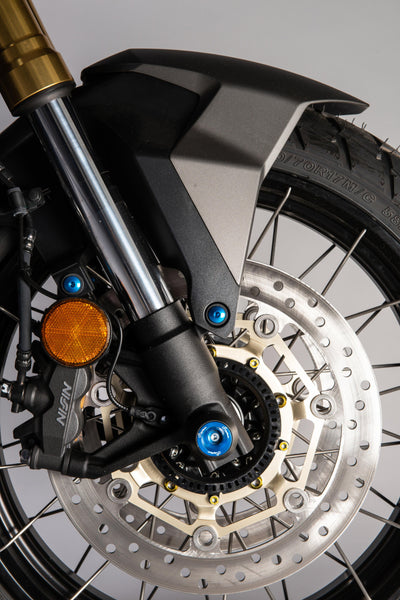 LighTech WAPHO406COB cobalt-blue front axle slider installed, wider fork view; paddock stand, stand supports, chain adjusters, chain guard, coloured fasteners and motorcycle accessories are not included.