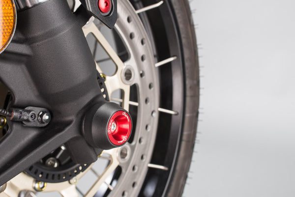 LighTech WAPHO406ROS red front axle slider installed, opposite-angle detail; paddock stand, stand supports, chain adjusters, chain guard, coloured fasteners and motorcycle accessories are not included.