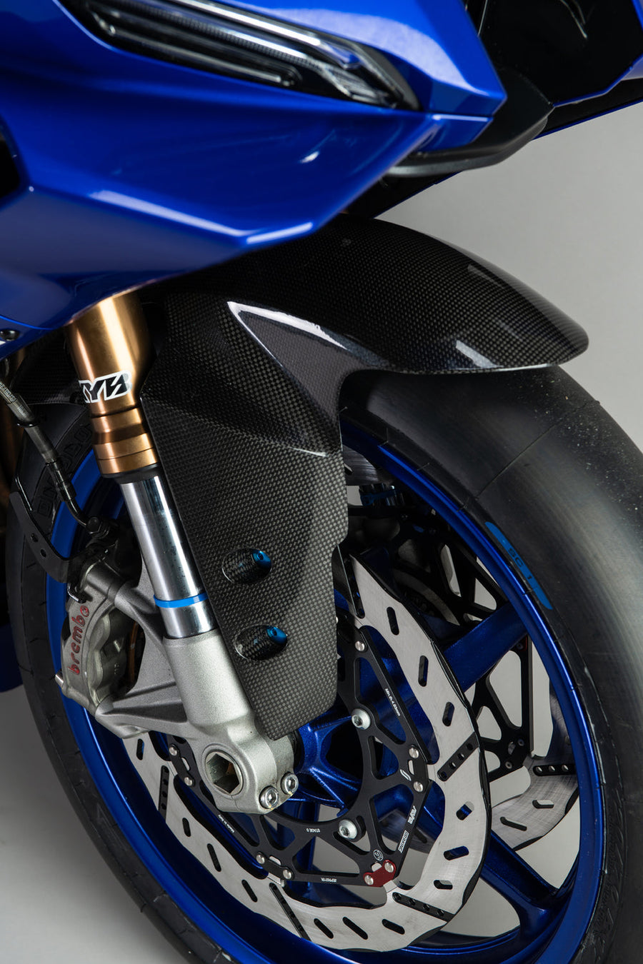 LighTech CARY0910 gloss carbon front mudguard. Installed image shows an optional coloured bolt kit, which is not included. Motorcycle, wheel, brakes and other accessories are separate.