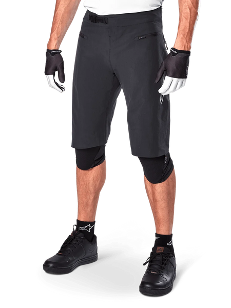 Alpinestars A-Aria Shorts, Mountain Biking Shorts, Black, knee-length with front zippered pockets and adjustable ratchet waist buckle, worn with black knee pads, socks, and cycling gloves