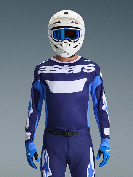 Motocross rider wearing Alpinestars 2026 Racer Riway Jersey, UCLA Blue and White with white 'astars' logo on chest, white helmet with blue goggles, matching motocross pants and blue gloves, coordinated off-road racing gear