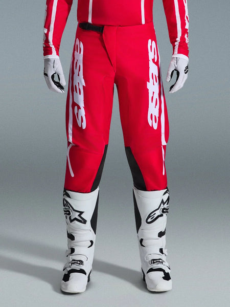 Alpinestars 2026 Fluid Apex Pants, Motocross Pants, Red and White, featuring large white Astars logos on the thighs and black inner knee panels, worn with matching white and black boots and gloves for a complete off-road racing look.