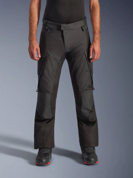 Alpinestars Andes V4 Drystar Pants, Motorcycle Adventure Touring Pants, Black with gray panels, featuring reinforced knee patches and thigh cargo pockets, worn with black riding boots, waterproof textile construction for all-weather riding