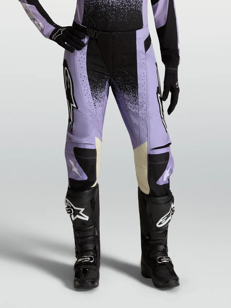 Stella Techstar Swan Pants, women's motocross racing pants in Light Violet and Black with cream leather accents, paired with black off-road boots.