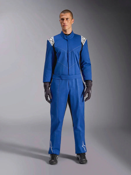 Male model wearing Alpinestars Kart Indoor V2 Suit in Blue, one-piece karting suit with white star logos on shoulders and shins, white contrast stitching, elastic waist belt, styled with black racing gloves and footwear, designed for recreational track use