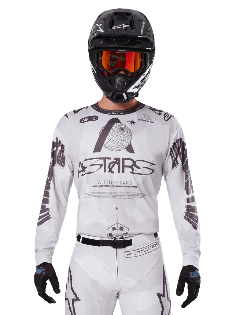 Alpinestars 2025 Racer Hollow Jersey, Motocross Jersey, White and Black, worn with matching white MX pants and a black helmet with orange goggles, featuring bold Alpinestars branding and globe graphics, professional off-road racing gear