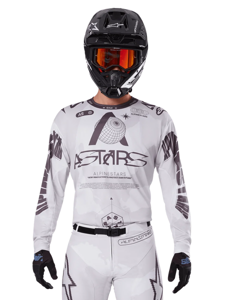 Alpinestars 2025 Racer Hollow Jersey, Motocross Jersey, White and Black, worn with matching white MX pants and a black helmet with orange goggles, featuring bold Alpinestars branding and globe graphics, professional off-road racing gear