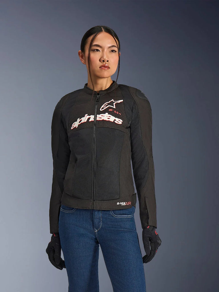 Woman wearing Alpinestars Stella SMX Air Jacket, Black White Red Fluo, textile motorcycle jacket with ventilated mesh and white chest logo, styled with blue jeans and black riding gloves, feminine fit for sport riding