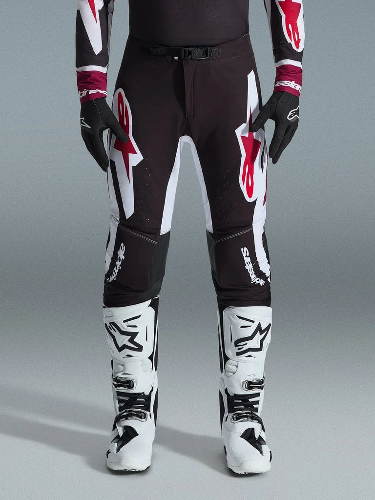 Alpinestars 2026 Supertech AFD Vista Pants, Motocross Pants, Black Red and White, featuring large graphic logos on the thighs and knees, worn with white racing boots and black gloves, athletic race-ready design for elite off-road competition