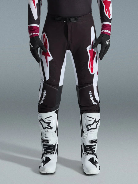 Alpinestars 2026 Supertech AFD Vista Pants, Motocross Pants, Black Red and White, featuring large graphic logos on the thighs and knees, worn with white racing boots and black gloves, athletic race-ready design for elite off-road competition