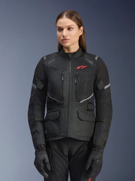 Alpinestars Stella Andes Air Drystar Jacket, Women's Motorcycle Touring Jacket, Black with gray accents and a small red logo, featuring mesh ventilation panels, a high collar, and multiple utility pockets, worn with matching riding gloves and pants