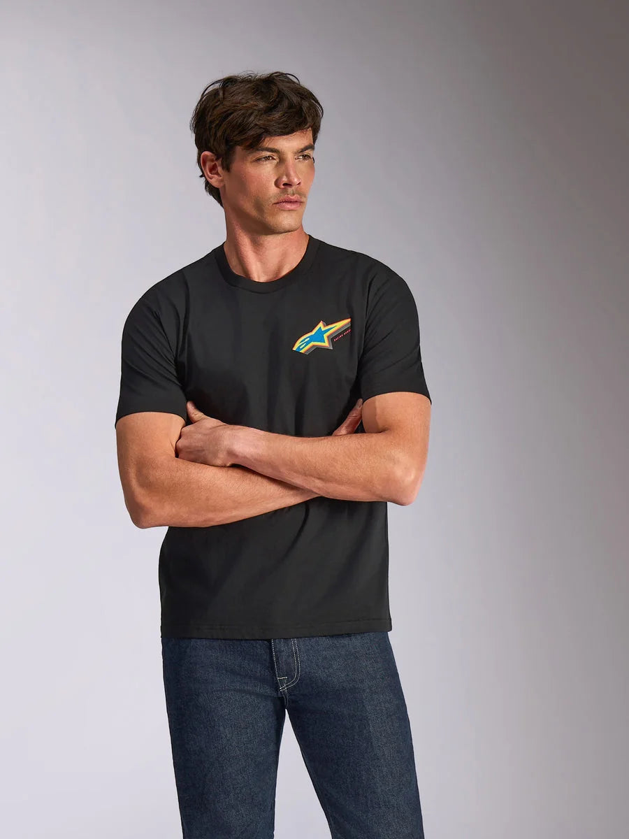 Alpinestars Angler CSF Tee, Short Sleeve T-Shirt, Black, Featuring a vibrant multi-color Astars logo on the chest, worn by a model with arms crossed and blue jeans, casual motorsport-inspired streetwear