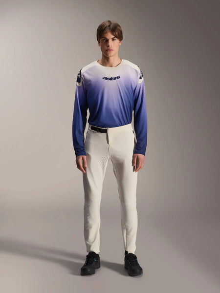Alpinestars A-Aria Elite Pants, Ecru Performance MTB Pants, off-white cycling trousers with laser-perforated thigh panels and magnetic buckle, worn with gradient blue long-sleeve jersey and black shoes, performance fit for trail riding
