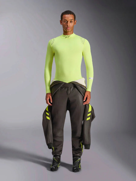Alpinestars ZX Evo V3 Top - Long Sleeve, Yellow Fluo, worn by a model with dark racing pants and boots, featuring a mock neck and athletic fit, fire-resistant base layer for professional auto racing