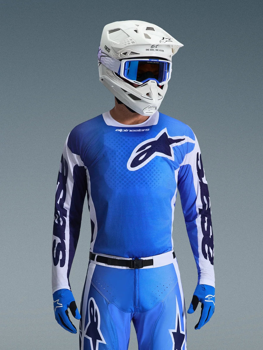 Alpinestars 2026 Racer Air Portl Jersey in Ucla Blue and White, motocross jersey featuring a breathable mesh construction and bold star logo, worn by a rider with matching pants, white helmet, and blue goggles for a coordinated off-road racing gearset.