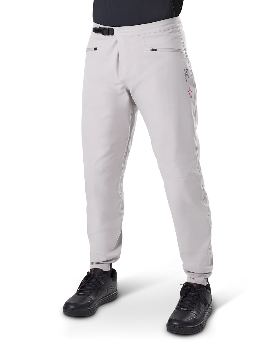 Alpinestars A-Dura Waterproof Pants, Mountain Bike Pants, Titanium Gray, featuring a black ratchet waist closure and zippered hand pockets, tapered legs with elastic cuffs, worn with black shoes, durable 3L waterproof construction for off-road cycling