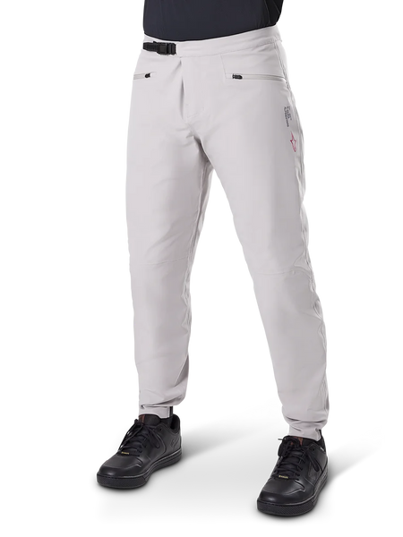 Alpinestars A-Dura Waterproof Pants, Mountain Bike Pants, Titanium Gray, featuring a black ratchet waist closure and zippered hand pockets, tapered legs with elastic cuffs, worn with black shoes, durable 3L waterproof construction for off-road cycling