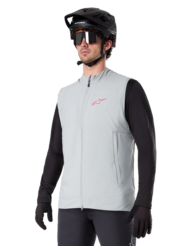 Alpinestars A-Dura Thermal Vest, Titanium Gray, cycling insulated vest, worn over a black long-sleeve shirt with a black mountain bike helmet and gloves, featuring a pink chest logo and vertical zippered side pockets