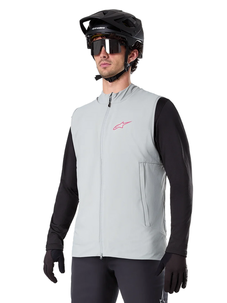 Alpinestars A-Dura Thermal Vest, Titanium Gray, cycling insulated vest, worn over a black long-sleeve shirt with a black mountain bike helmet and gloves, featuring a pink chest logo and vertical zippered side pockets