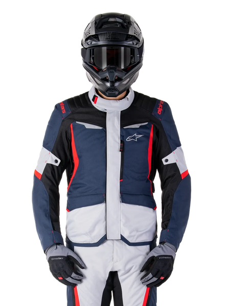 Alpinestars ST-1 Waterproof Jacket, Adventure Touring Jacket, Dark Blue Black and Bright Red, worn with a black adventure helmet and grey gloves, featuring light grey panels and red accents on shoulders and zippers, sleek design with Alpinestars branding on chest, durable waterproof gear for motorcycle riding