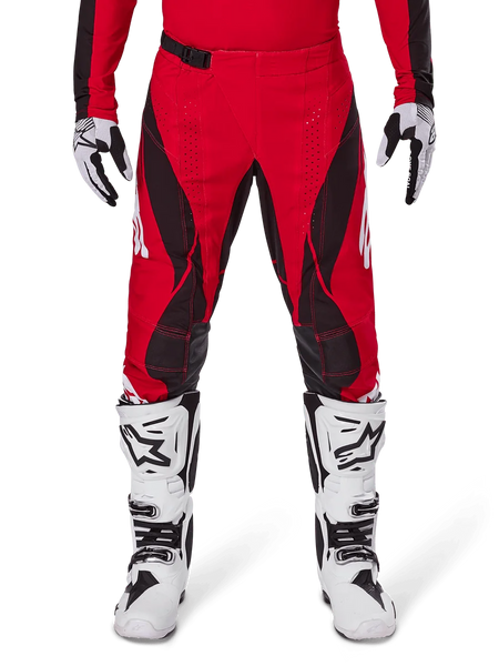 Alpinestars 2025 Techstar Dreem Pants, Motocross Pants, Bright Red and Black, featuring angular patterns and laser-cut ventilation holes, worn with white motocross boots and matching gloves for off-road racing