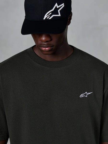 Alpinestars Essentials Ageless SS Tee, Short Sleeve T-Shirt, Off Black, featuring a small white Alpinestars logo on the chest, worn with a black logo baseball cap, casual motorsport streetwear style