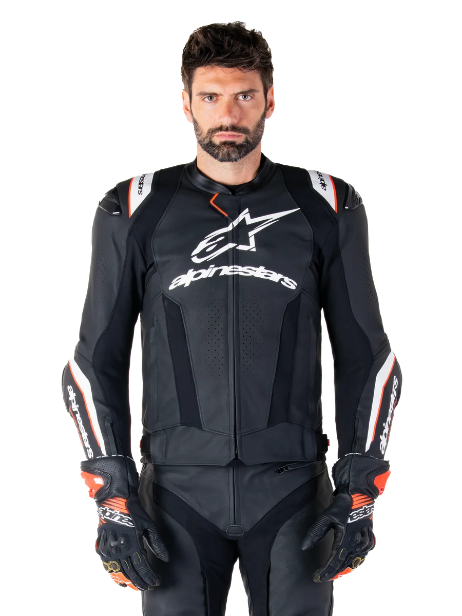 Alpinestars Missile V3 Ignition Leather Jacket, Black with white and red accents, worn by a male model with matching racing gloves and pants, MotoGP-derived sport motorcycle jacket with bold branding
