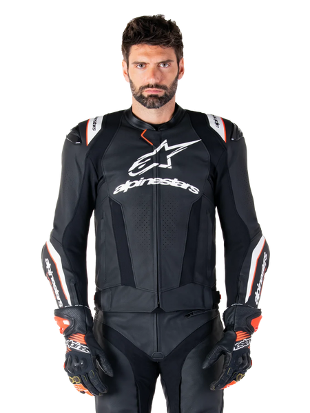 Alpinestars Missile V3 Ignition Leather Jacket, Black with white and red accents, worn by a male model with matching racing gloves and pants, MotoGP-derived sport motorcycle jacket with bold branding