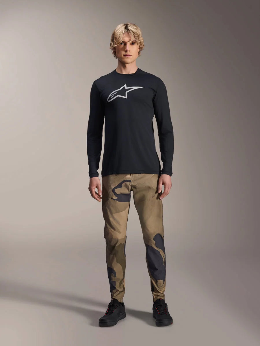 Alpinestars A-Dura Camo Pant, MTB Cycling Pants, Brown and Green Camouflage, worn with a black long-sleeve jersey and black shoes, sporty mountain bike style with durable stretch fabric