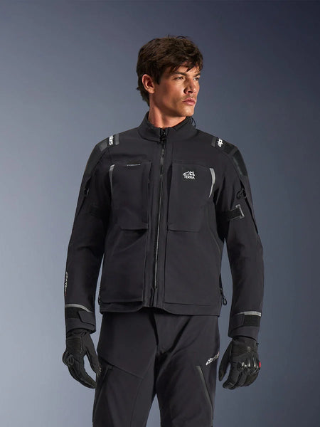 Alpinestars Andes Pro Drystar® XF Jacket, black and dark gray motorcycle adventure touring jacket, worn with matching pants and gloves, featuring technical laminated shell construction, ALL TERRA chest logo, reflective details, and adjustable cuffs