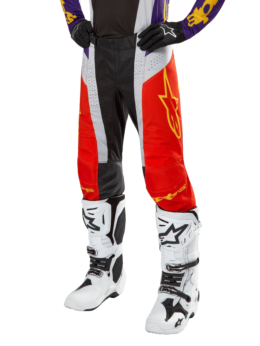 Alpinestars 2024 Techstar Ocuri Pants, Motocross Racing Pants, Hot Orange, Black, and White with Yellow Star Graphic, worn with purple jersey and white boots, durable performance gear for off-road competition