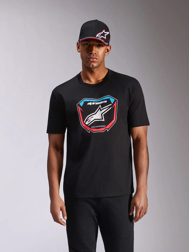 Alpinestars Plate CSF Tee, Short Sleeve T-Shirt, Black, featuring a front MX plate graphic with white logo and red and blue accents, worn by model with matching black cap, casual motorsport streetwear
