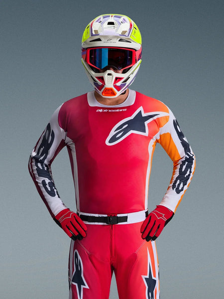 Alpinestars 2026 Racer Portl Jersey, Red Motocross Jersey, front view of a rider wearing matching red pants and gloves, featuring a black and white star logo on the chest and white sleeves with black branding, paired with a multi-colored white and yellow helmet, complete professional off-road racing gear.
