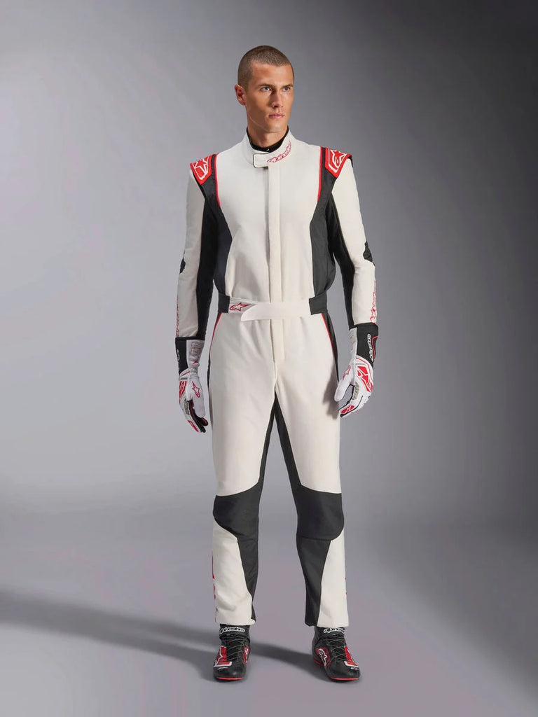 Alpinestars GP Tech V4 Suit, White Black and Red one-piece auto racing suit, worn by a male model with matching racing gloves and shoes, featuring red logos on the shoulders and black side panels, professional motorsport gear for track use.