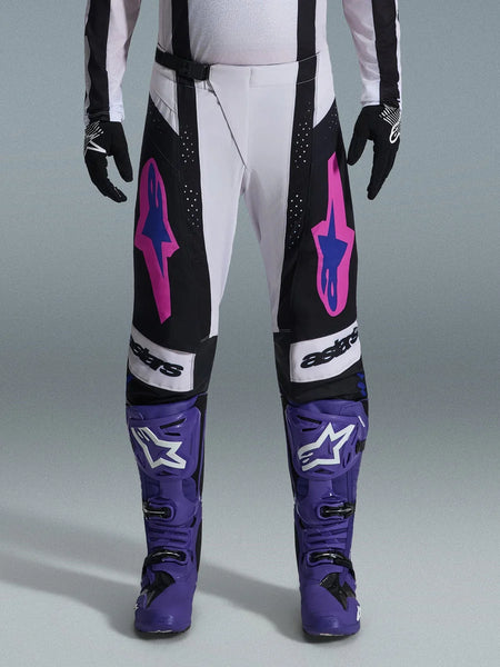 Alpinestars 2026 Techstar Knif Pants, Motocross Racing Pants, Black, White, and Purple with Pink and Blue accents, worn with purple racing boots and black gloves, featuring ergonomic racing cut and bold logo graphics for off-road performance
