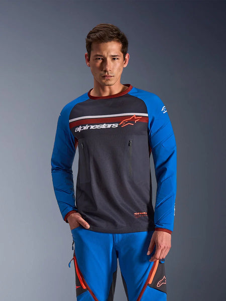 Man wearing Alpinestars Maxdura Dual Jersey in Deep Gray and Royal Blue with orange accents, featuring a full mesh torso and zippered chest pockets, paired with matching blue adventure riding pants, technical dual-sport and off-road apparel