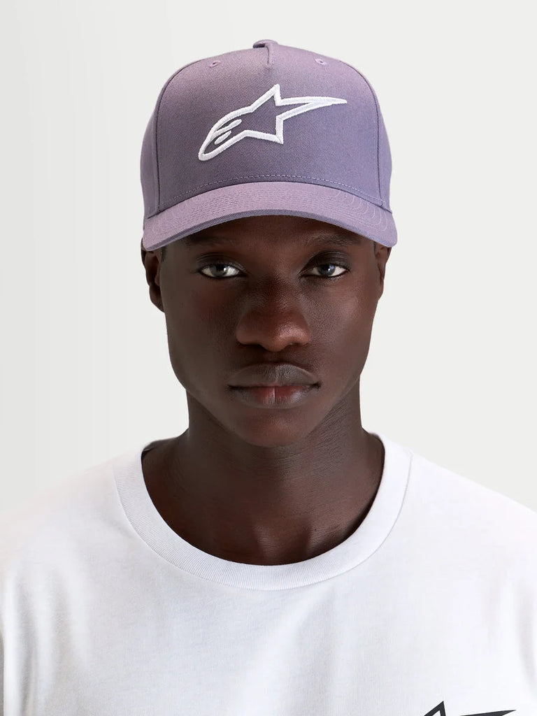 Alpinestars Ageless Snapback Hat, curved bill sportswear cap, dusty purple and white, worn by a model showcasing the front embroidered 3D Astars logo and structured twill profile
