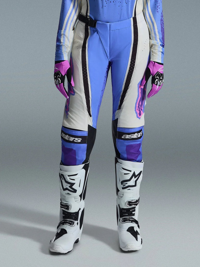 Alpinestars 2026 Woman Stella Techstar Nomur Pants, Motocross Pants, Light Blue, Off White, and Black, worn with white motocross boots and pink and black gloves, featuring 'astars' branding on the knees and a technical multi-panel design for female riders.