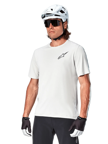 Alpinestars A-Aria Astar Short Sleeve Jersey, White Dove, worn by a cyclist with a white helmet and dark sunglasses, featuring a small black star logo on the chest, breathable performance gear for mountain biking