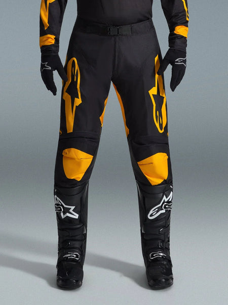 Alpinestars 2026 Racer Riway Pants, Motocross Pants, Yellow and Black, worn with black motocross gloves and black boots with white logos, featuring large yellow Alpinestars logos on the thighs and yellow knee panels, durable design for off-road racing performance