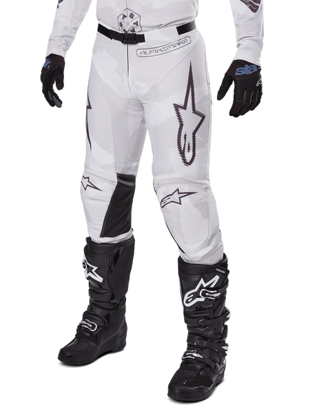 Alpinestars 2025 Racer Hollow Pants, Motocross Pants, White and Grey Camo, featuring large black outlined star logos and black leather inner knee panels, worn with black motocross boots and gloves, durable design for off-road racing.