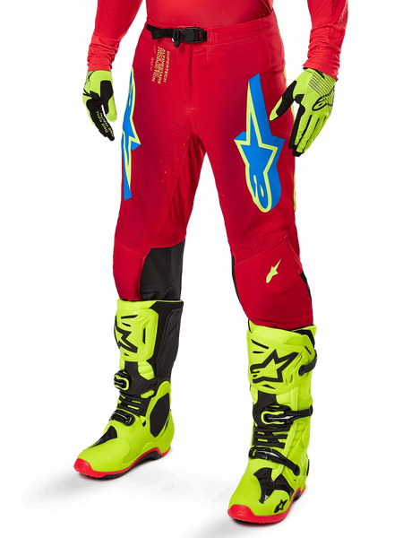 Alpinestars 2025 Supertech Maker Pants, Motocross Racing Pants, Bright Red with blue and yellow star logos, black knee panels, perforated ventilation, coordinated with neon yellow boots and gloves