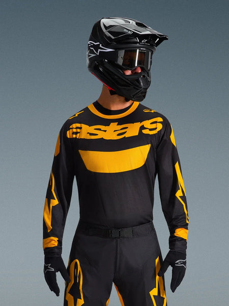 Motocross rider wearing the Alpinestars 2026 Racer Riway Jersey in Yellow and Black, featuring a bold yellow 'astars' logo across the chest, paired with coordinating black and yellow pants, a black helmet with goggles, and black gloves, professional off-road racing gear set.