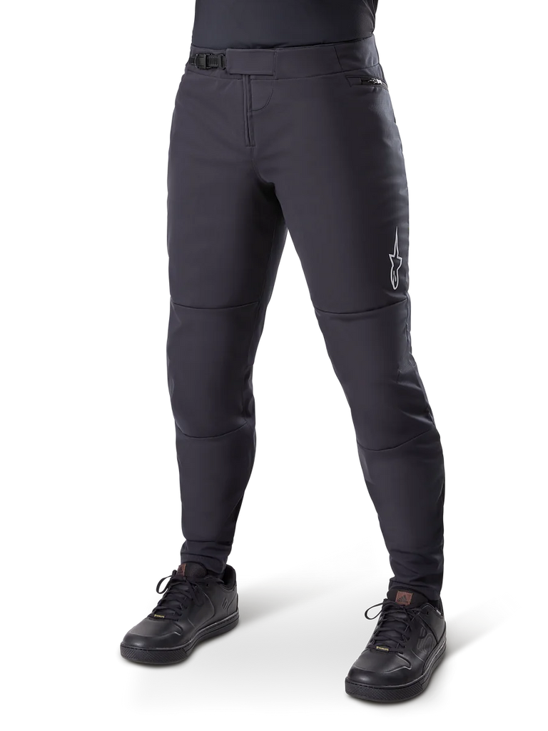 Alpinestars A-Dura Thermal Pant, Black Mountain Bike Pants, worn with black cycling shoes, featuring a ratchet waist closure, small white logo on the thigh, tapered fit for cold-weather riding