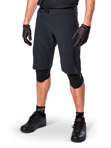 Alpinestars A-Aria Elite Shorts, Black Cycling Shorts, worn with matching black gloves and knee guards, featuring a magnetic buckle and laser-cut perforations, sleek design for off-road mountain biking