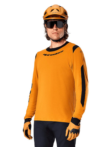 Alpinestars A-Dura Dri Wool Jersey - Long Sleeve, MTB Mountain Biking Jersey, Dark Gold and Black, featuring moisture-wicking merino wool blend and mesh panels, rider wearing matching helmet, sunglasses, and gloves
