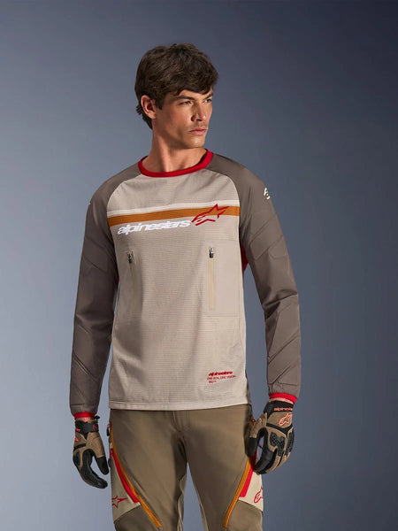 Alpinestars Maxdura Dual Jersey in Aluminum Walnut, adventure motorcycle jersey featuring a breathable mesh torso, walnut brown abrasion-resistant sleeves, and zippered chest pockets, worn by a model with matching off-road gear.