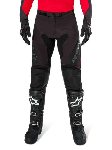Alpinestars Pro-Dura Pants, Black and Magnet Enduro Pants, worn with a red long-sleeve jersey and black motocross boots, featuring gray Alpinestars branding and durable ripstop construction for off-road riding