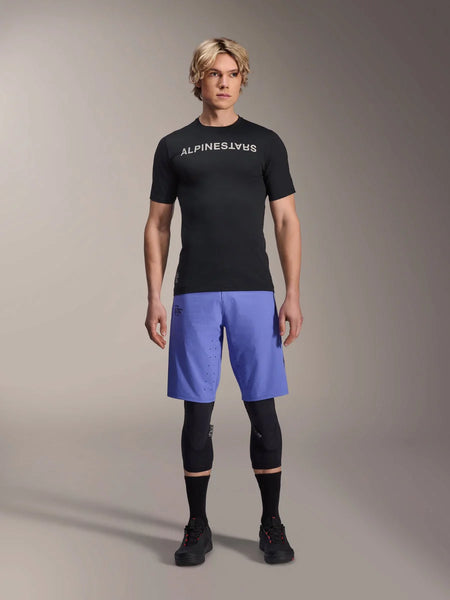 Alpinestars A-Aria Lite Short in Baja Blue, Men's MTB Shorts, worn with a black short-sleeve jersey and protective knee guards, featuring laser perforations for ventilation, mountain bike performance gear